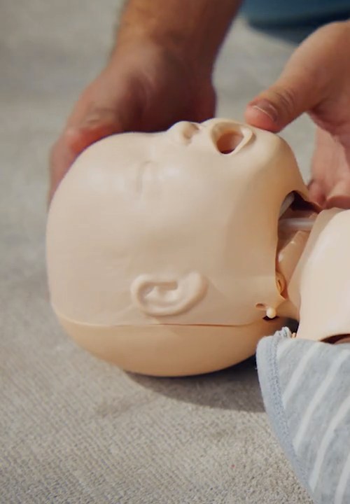 Übung an einer Baby-Puppe: Hand am Kopf